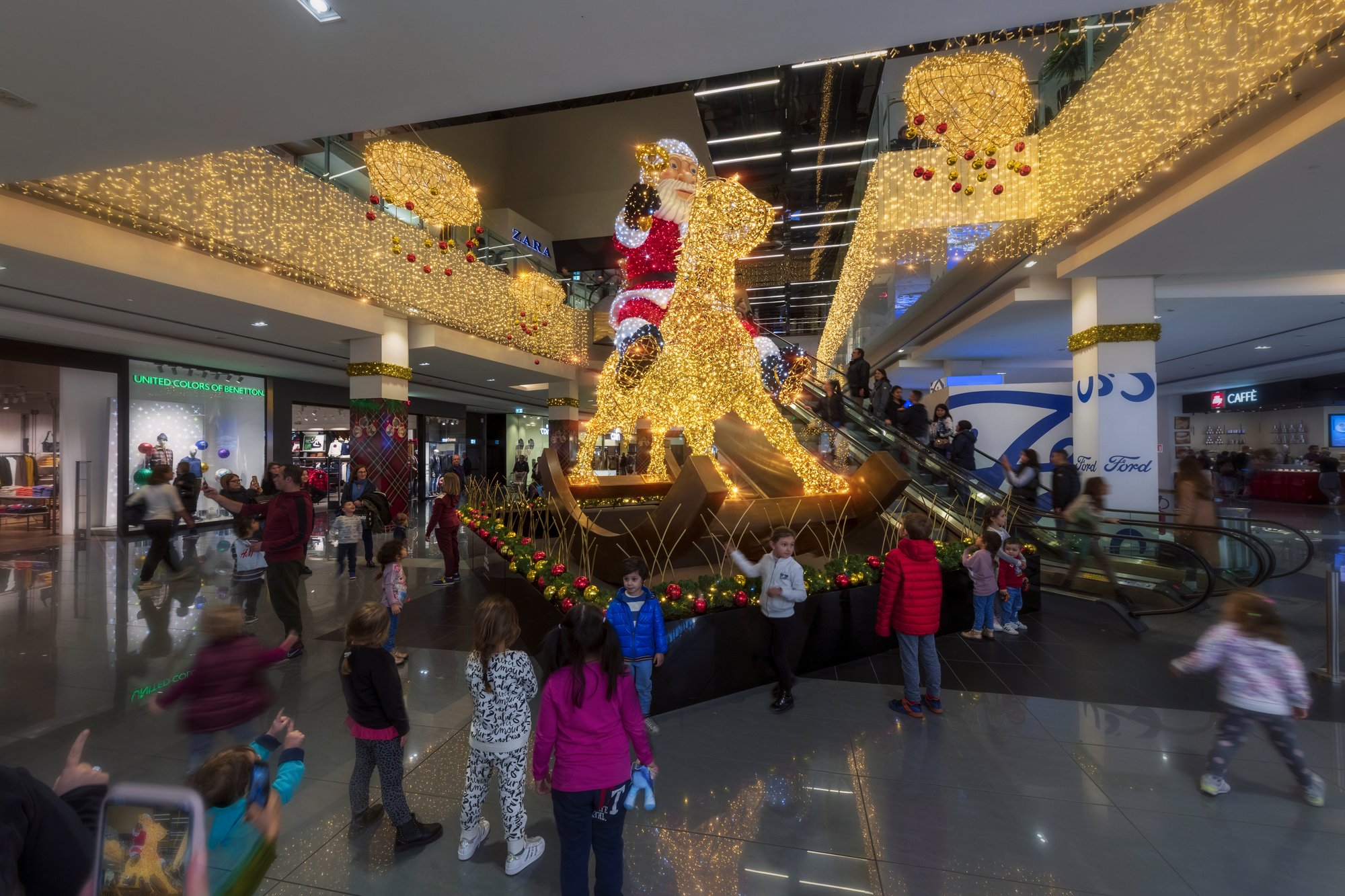 Babbo Natale su un cavallo a dondolo luminoso nella galleria commerciale
