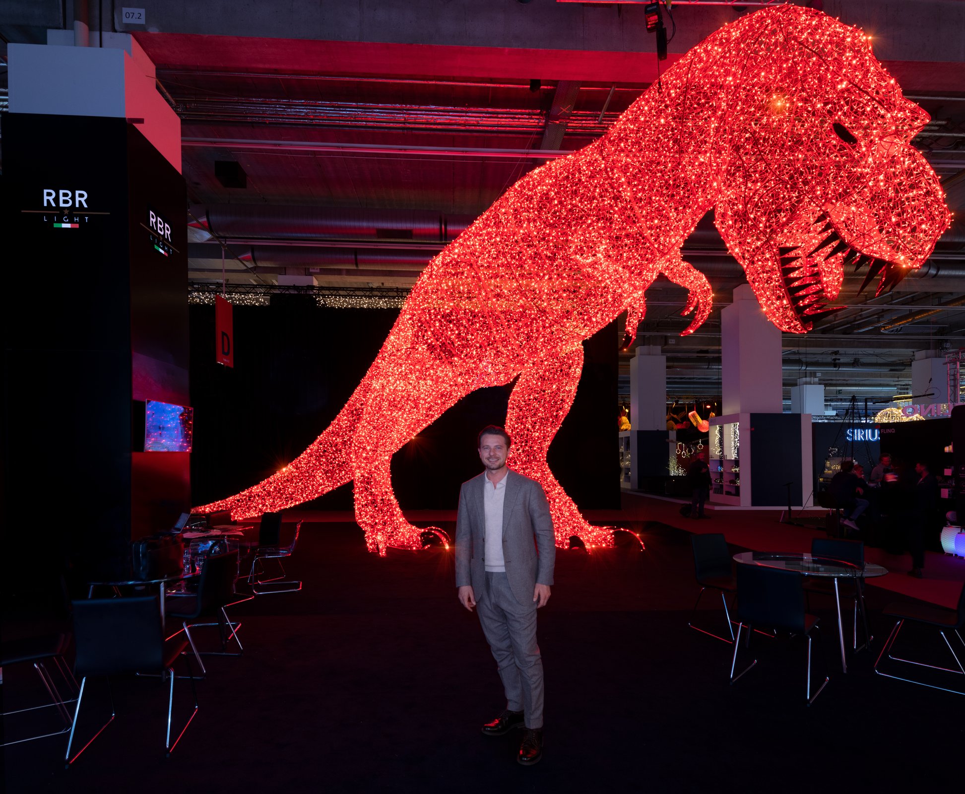 T-Rex luminoso con una persona che ne mostra la scala